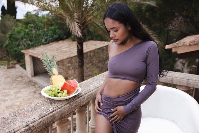 Liloo teases on a sunny Mallorca balcony in a purple dress, topless and playful with fruit nearby — Liloo #2