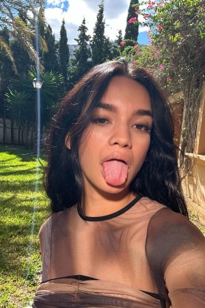 Dulce poses solo outdoors in sheer top under palm trees tongue out with sunlight on her skin — Dulce #1