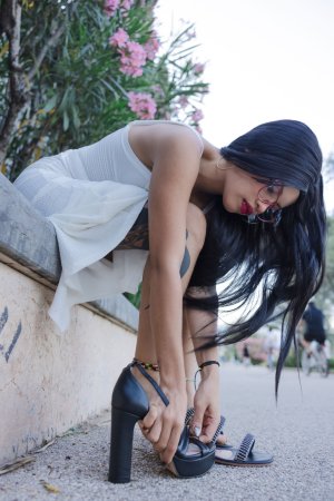 Lilith Baph crouches barefoot on concrete, tongue out, white dress riding high over her tattooed thighs — Lilith Baph #1