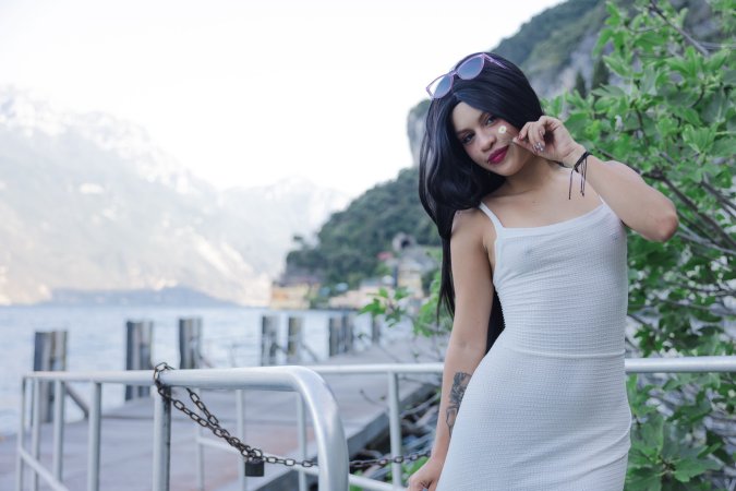 Lilith Baph crouches barefoot on concrete, tongue out, white dress riding high over her tattooed thighs — Lilith Baph #6