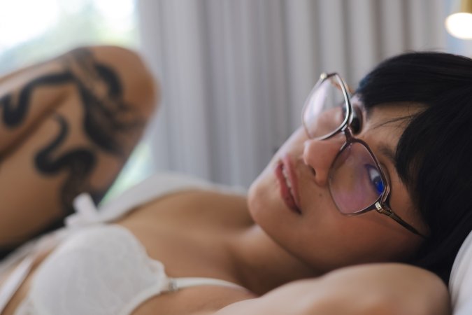 Lilith Baph smiling in white lingerie on bed fingers her wet pussy with blue nails and glasses — Lilith Baph #6