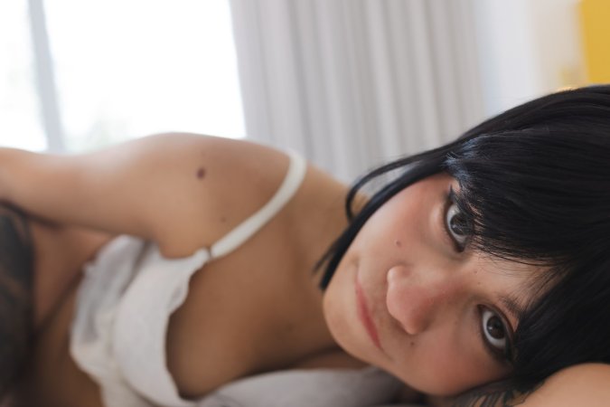 Lilith Baph smiling in white lingerie on bed fingers her wet pussy with blue nails and glasses — Lilith Baph #20
