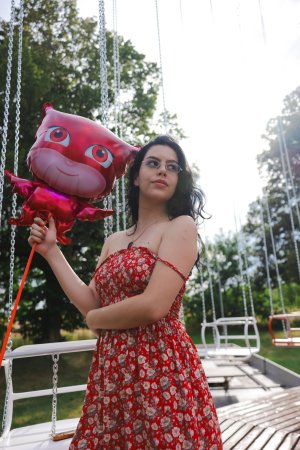 Sally Hunter laughs on a swing ride in a red dress holding a plush toy surrounded by trees and a soccer goal — Sally Hunter #2
