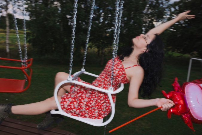 Sally Hunter laughs on a swing ride in a red dress holding a plush toy surrounded by trees and a soccer goal — Sally Hunter #4