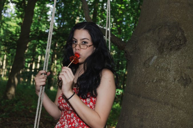 Sally Hunter laughs on a swing ride in a red dress holding a plush toy surrounded by trees and a soccer goal — Sally Hunter #14