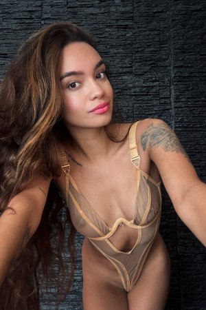 Dulce in sheer gold lingerie posing against dark stone wall teasing curves and tattoos — Dulce #17