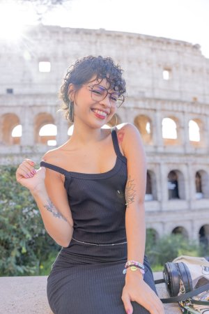 Lilith Baph poses solo in Rome with the Colosseum behind her, black dress and hoop earrings on display — Lilith Baph #3