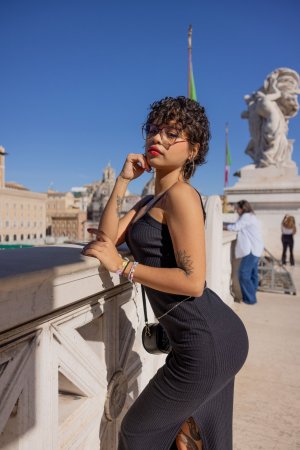 Lilith Baph poses solo in Rome with the Colosseum behind her, black dress and hoop earrings on display — Lilith Baph #6