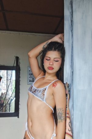 Lilith Baph in white bikini poses with leg up showcasing her tattooed curves and braids indoors — Lilith Baph #3