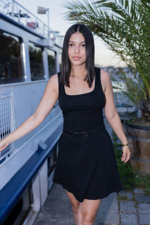 Gia Rosse leans against stone wall in black dress outdoors posing with gold necklace and wristwatch — Gia Rosse #3