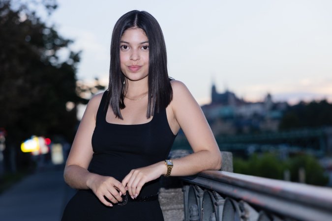 Gia Rosse leans against stone wall in black dress outdoors posing with gold necklace and wristwatch — Gia Rosse #10