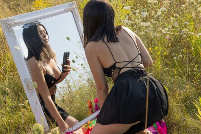 Gia Rosse solo in a sunlit meadow posing with her phone then slipping fingers under her skirt — Gia Rosse #1