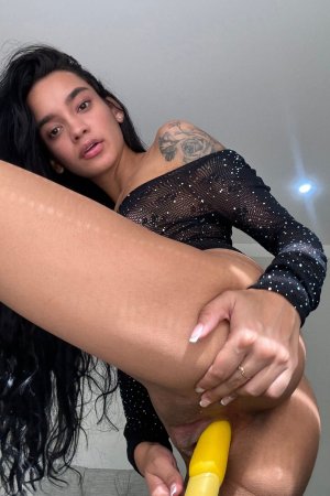 Dulce teases with her yellow toy in sheer black lingerie, legs spread wide on the couch — Dulce #1