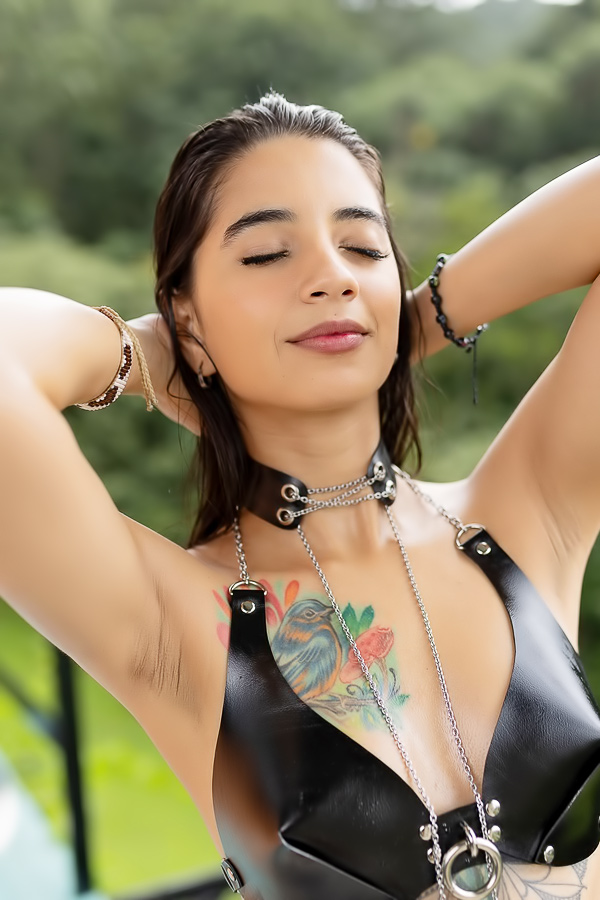 Tormenta poses in black leather lingerie on a rainy balcony her wet hair clinging to tattooed skin