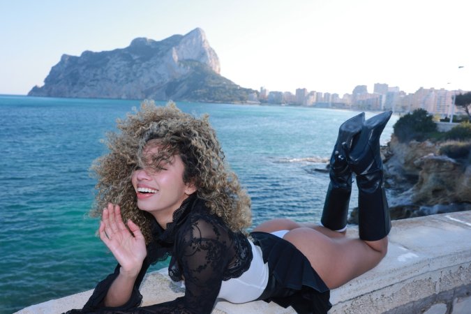 Valery Ponce stands poised on the Spanish coast, blonde curls framing her face as she poses in black boots and lace, sunlight tracing every curve — Valery Ponce #15