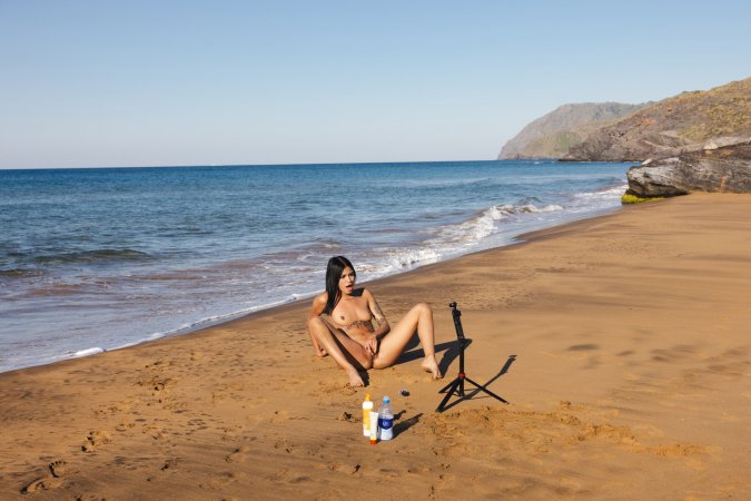 Sofia sitting on a tiled bench in sheer beaded lingerie, sunlight glinting off her tattooed skin — Sofia #14
