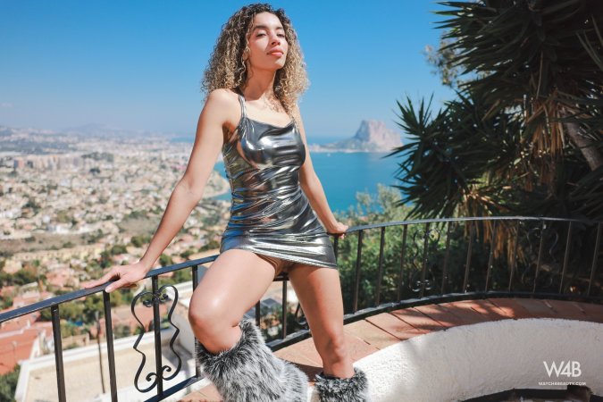 Valery Ponce poses in silver dress and fur boots on balcony overlooking the city skyline — Valery Ponce #1