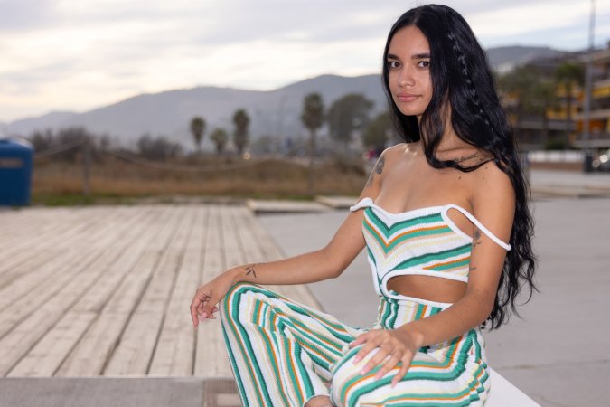 Dulce, beach breeze teasing her striped jumpsuit, whispers secrets only her tattoos know — Dulce #7