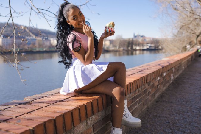 Sofi Vega licks ice cream by the river in pink top and white skirt, smiling for the camera — Sofi Vega #2