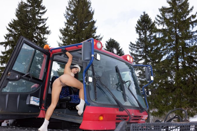 Topless brunette Iris Lucky in white beanie and bodysuit sits on red truck in evergreen trees — Iris Lucky #4