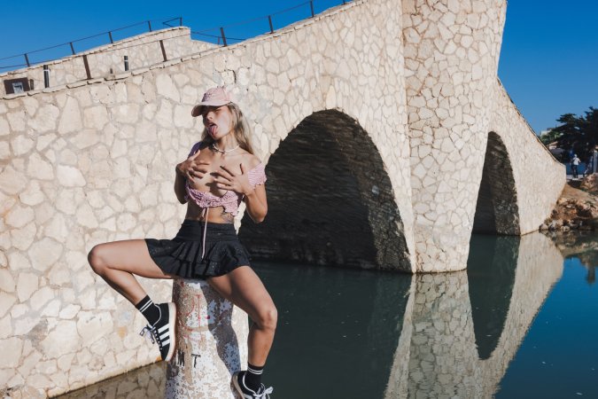 Irene Rouse spreads wide on stone wall under blue sky, solo pose showing off her gymnast flexibility — Irene Rouse #5