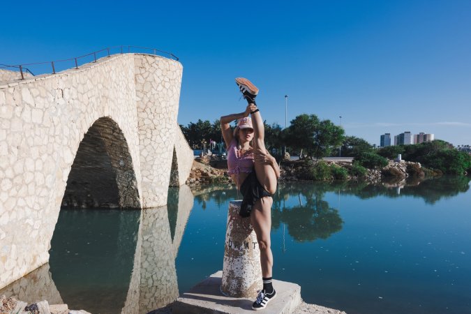 Irene Rouse spreads wide on stone wall under blue sky, solo pose showing off her gymnast flexibility — Irene Rouse #7
