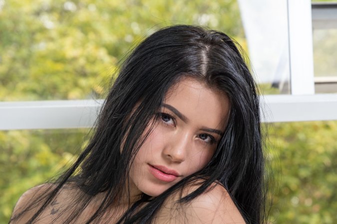 Paolina in lace lingerie posing on a white bed by the window with her black hair flowing — Paolina #8