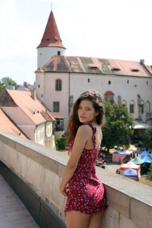 Irene Rouse in red floral dress poses solo against stone wall under Prague sun heat — Irene Rouse #1