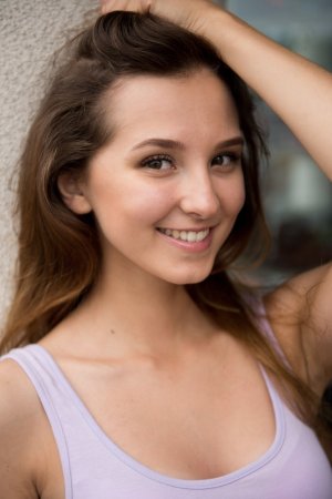 Milana in white dress and black heels posing solo outdoors leaning against planters and walls — Milana #16