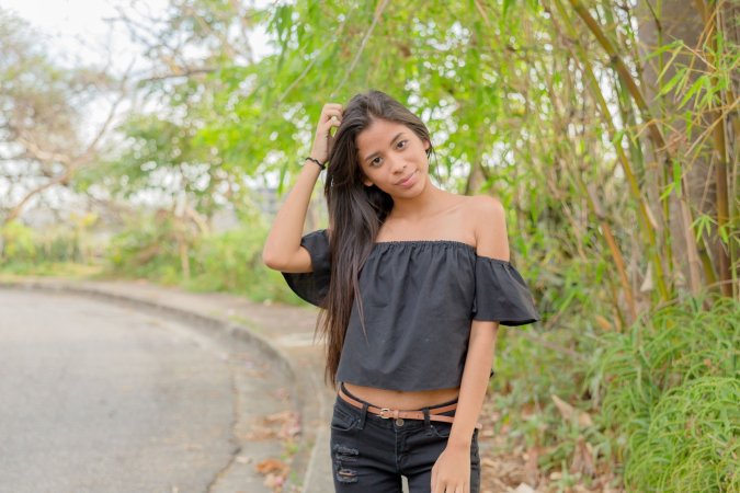 Karin Torres poses solo on a leafy path, black off shoulder top riding up over her hips, long hair swaying with each turn — Karin Torres #2