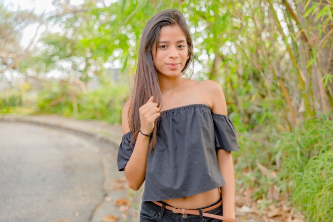 Karin Torres poses solo on a leafy path, black off shoulder top riding up over her hips, long hair swaying with each turn — Karin Torres #4