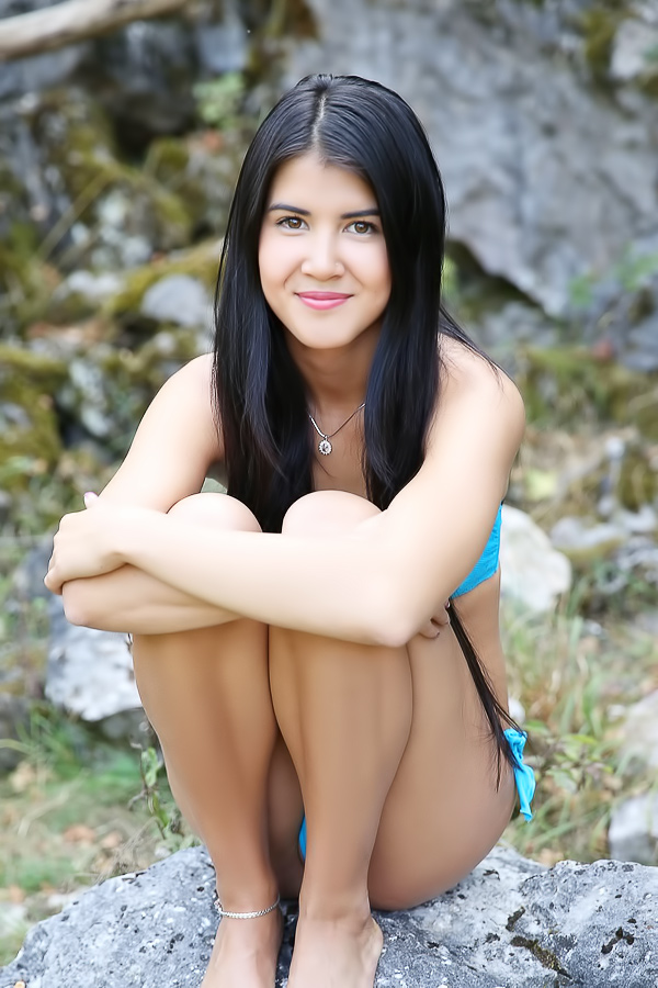Lady Dee commands the rocks barefoot, topless in camo shorts, teasing with a wild outdoor vibe