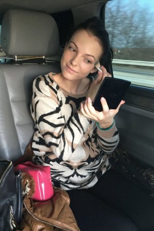 Sapphira applying makeup in car wearing tiger print sweater smiling with natural light and pink bag nearby — Sapphira #1