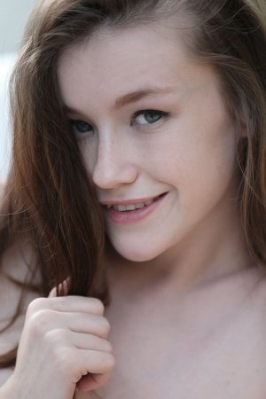 Emily spreading her legs outdoors, smiling while posing nude on white pillows in natural light — Emily #17